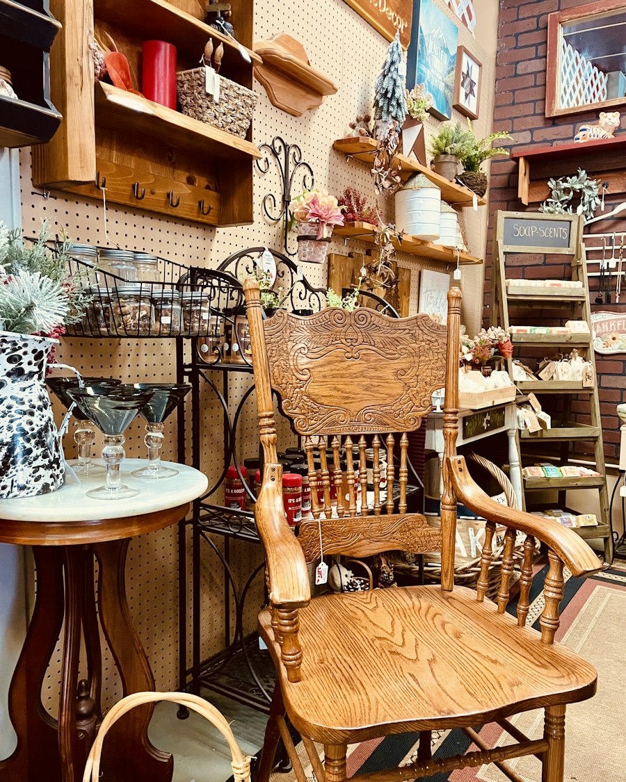 A carved oak chair with a hanging price tag in a crowded antique shop