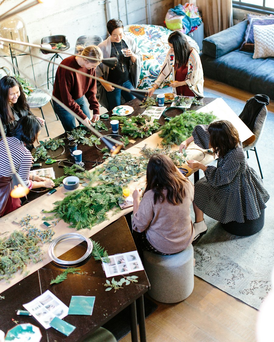 Women making wreaths from greenery around a long workshop table